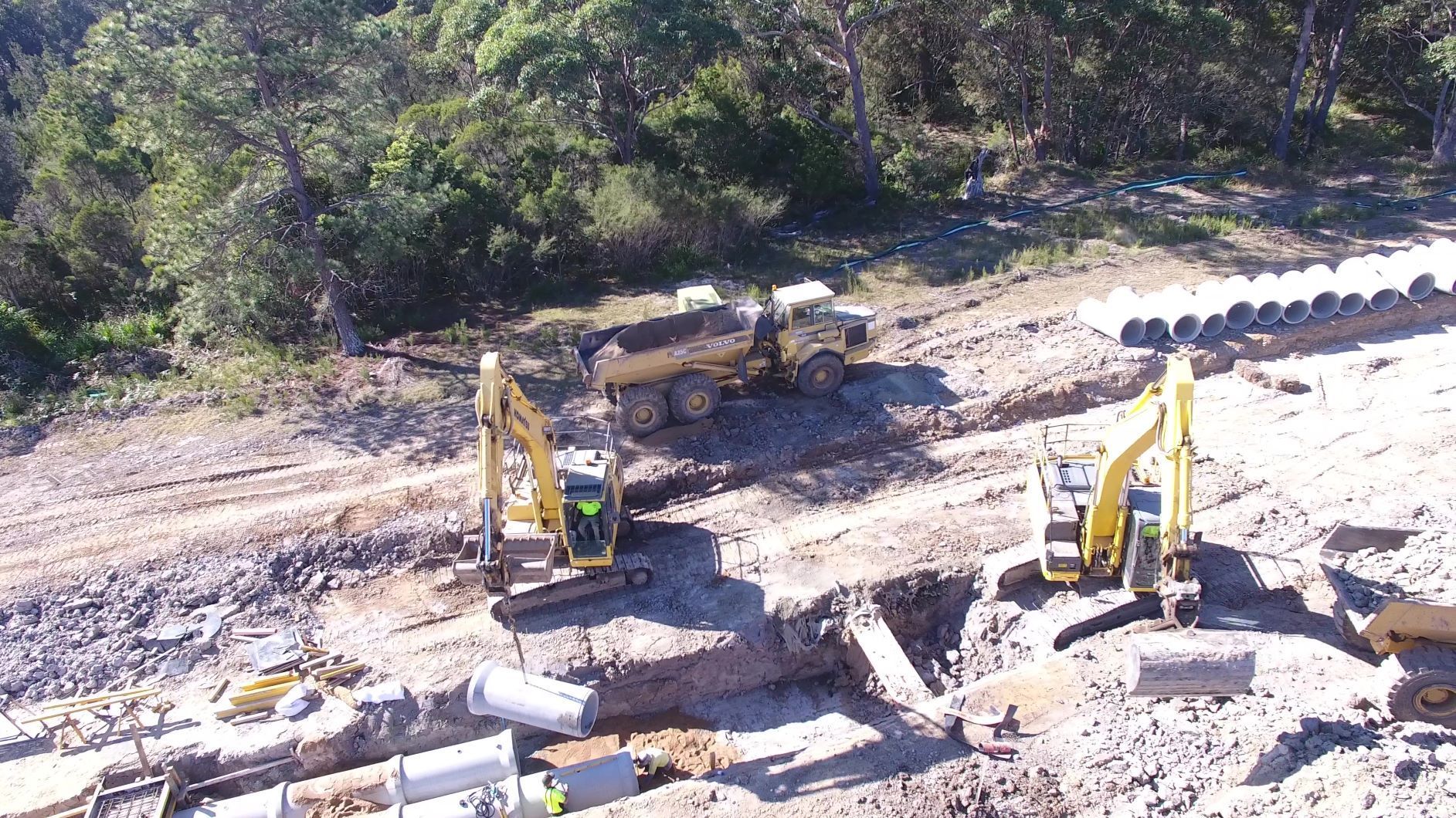 An aerial view of a construction site with a dump truck and excavators.