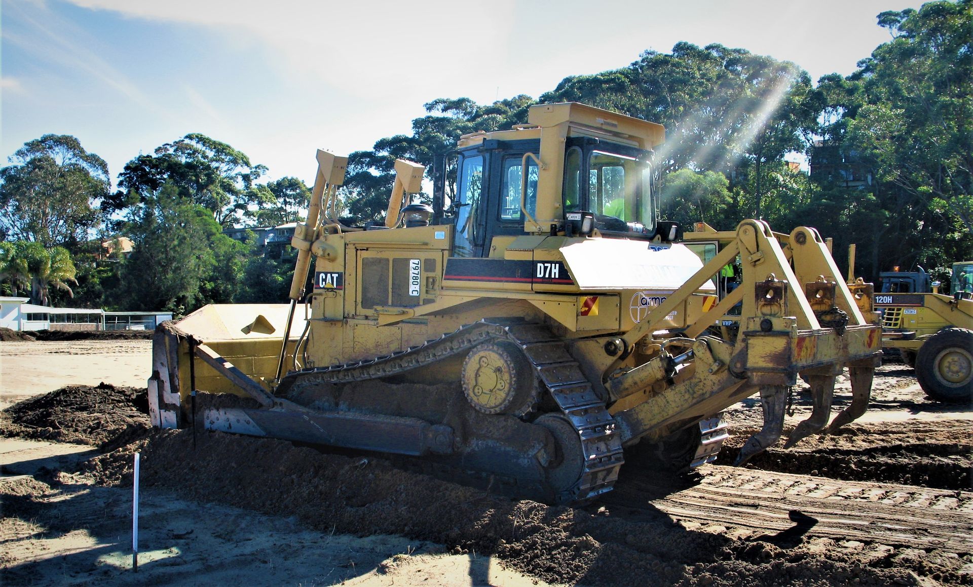 A large yellow bulldozer is parked in a dirt field