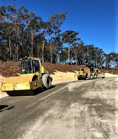 A yellow tractor is driving down a dirt road.