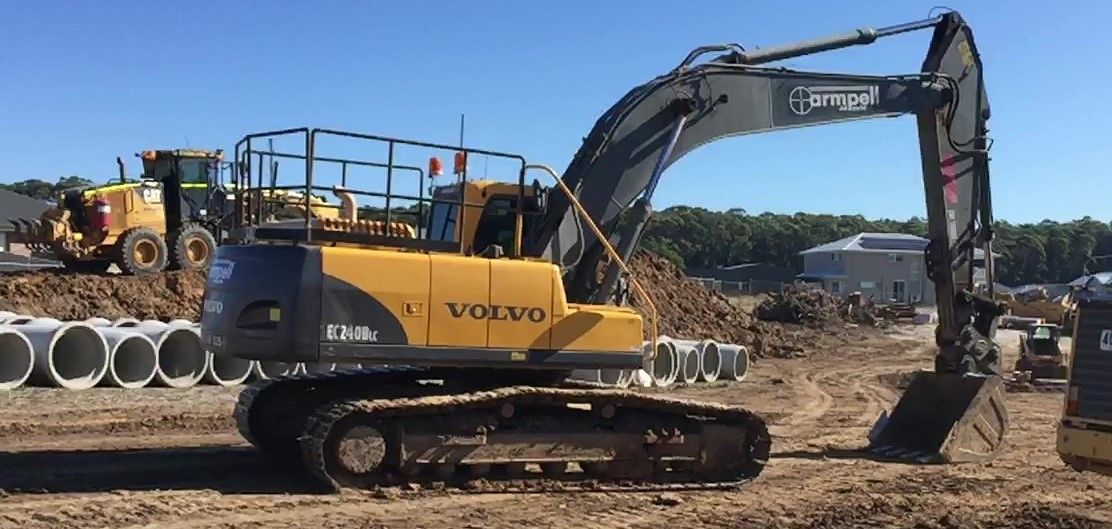 A yellow and black excavator is parked in a dirt field.