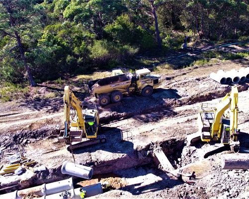 An aerial view of a construction site with a dump truck and excavators.