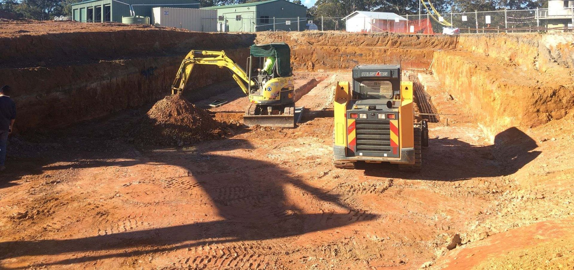 A yellow excavator is digging a hole in the dirt