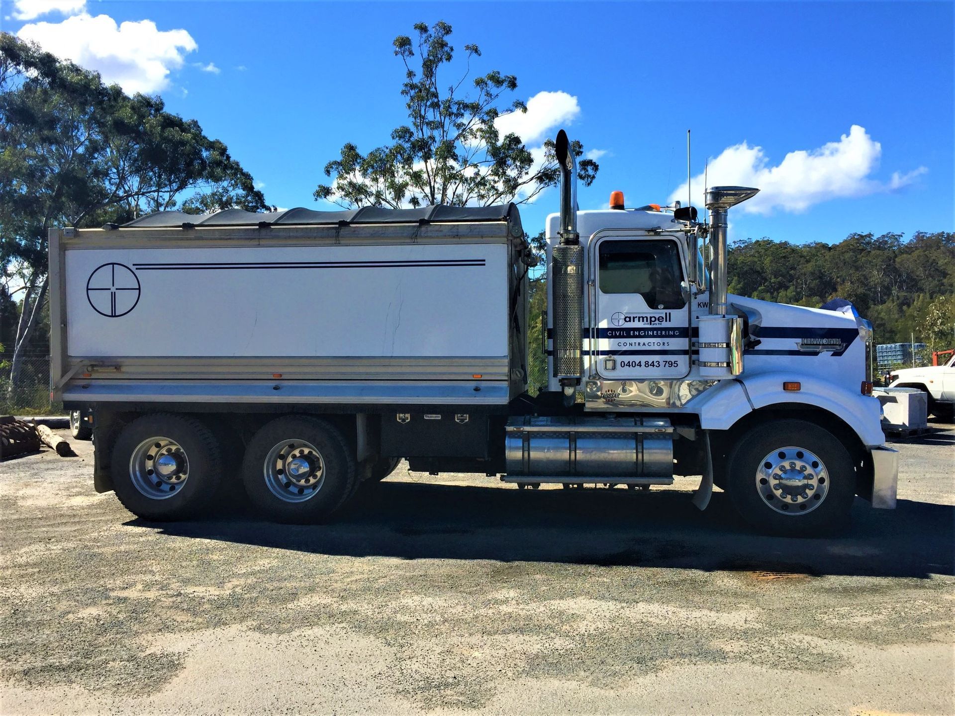 A large white truck is parked in a gravel lot.