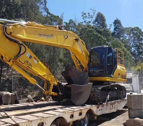 A yellow excavator is sitting on top of a trailer.