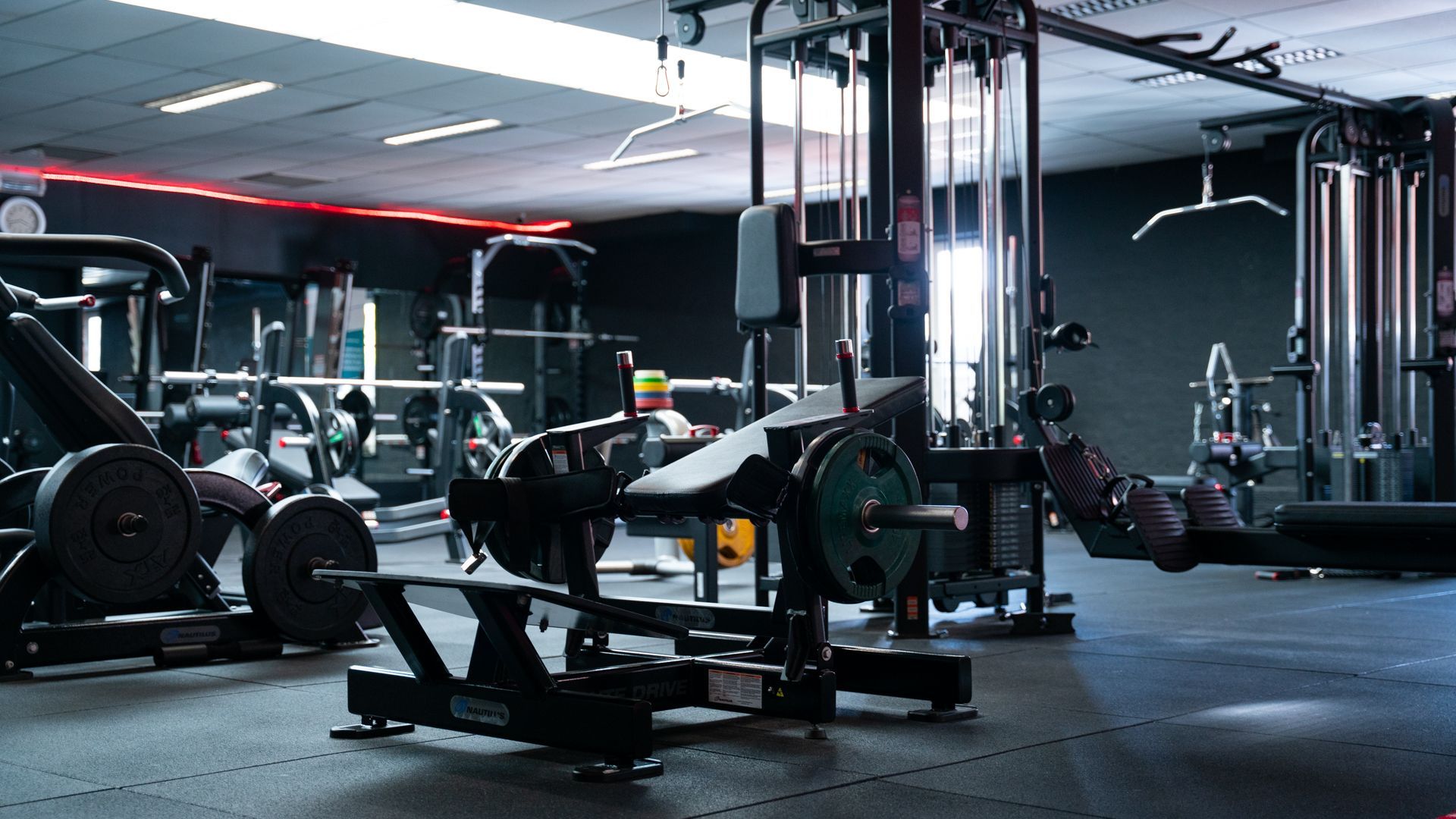 Een sportschool vol met veel fitnessapparatuur en een bank.