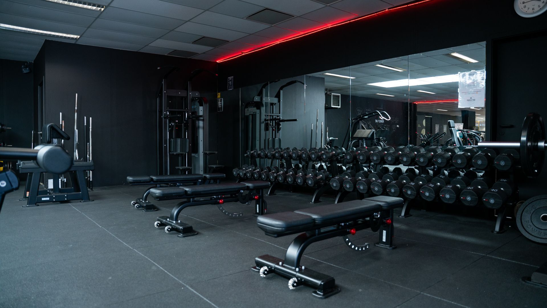 Een sportschool met veel dumbbells en bankjes