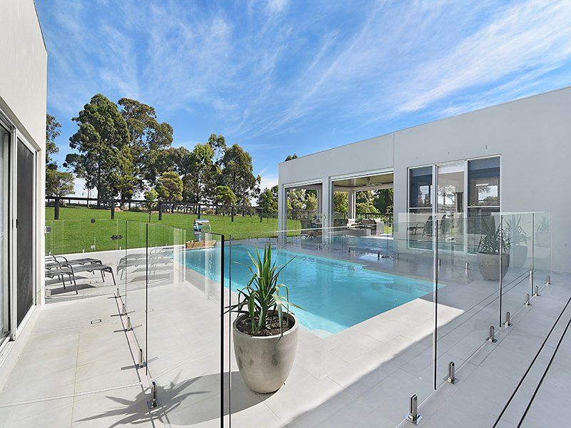 A Large Swimming Pool Surrounded By Glass Fence — Swimming Pool in Maitland, NSW