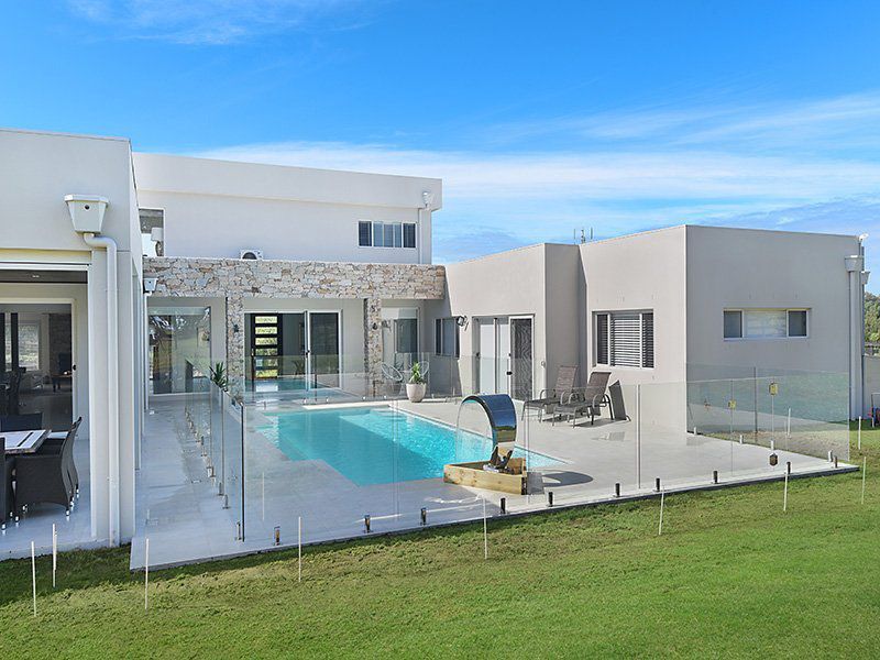 A Large White House With A Swimming Pool In The Backyard — Pool Installation in Newcastle, NSW