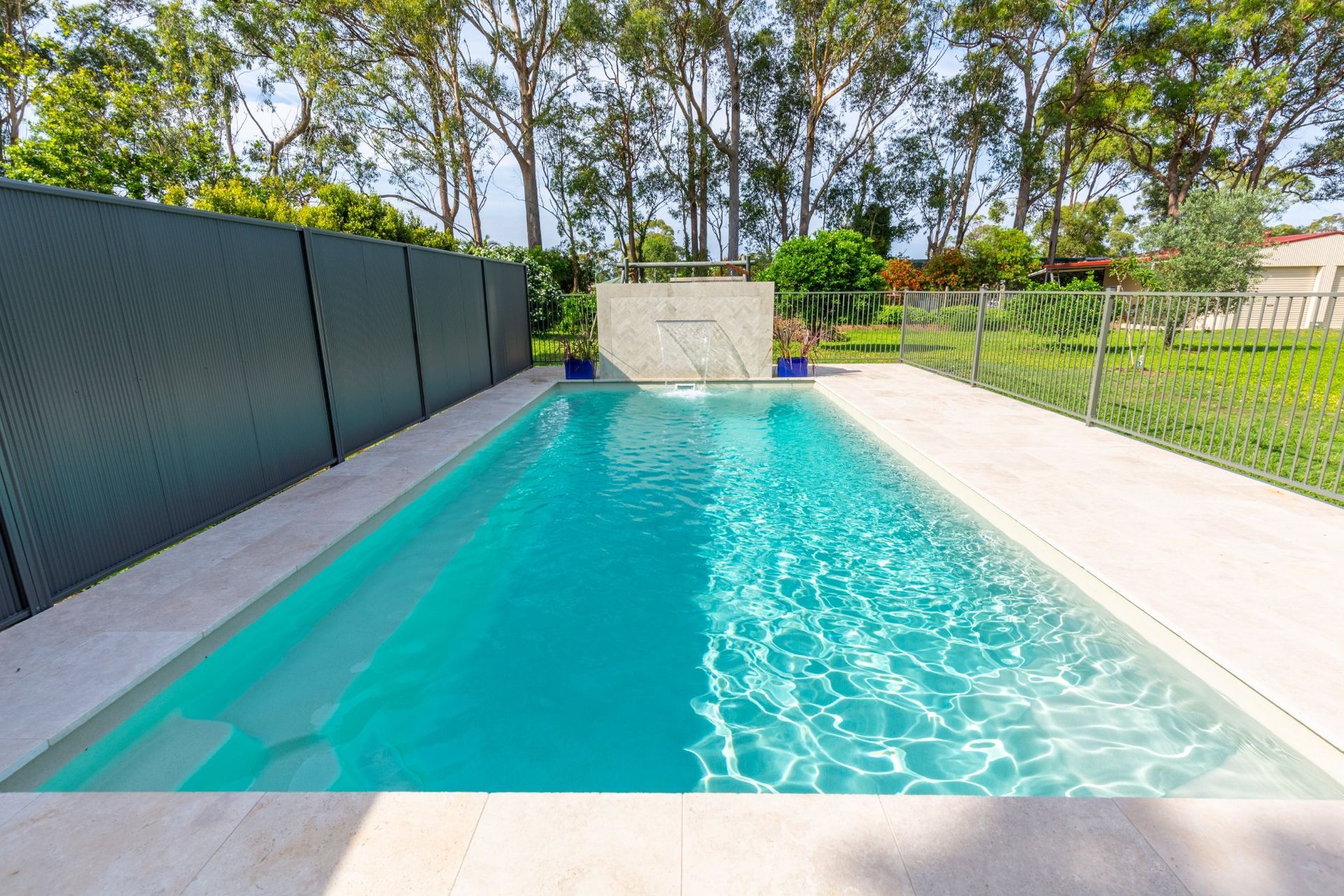 A Fence Surrounds A Large Swimming Pool In A Backyard — Swimming Pool in Port Stephens, NSW