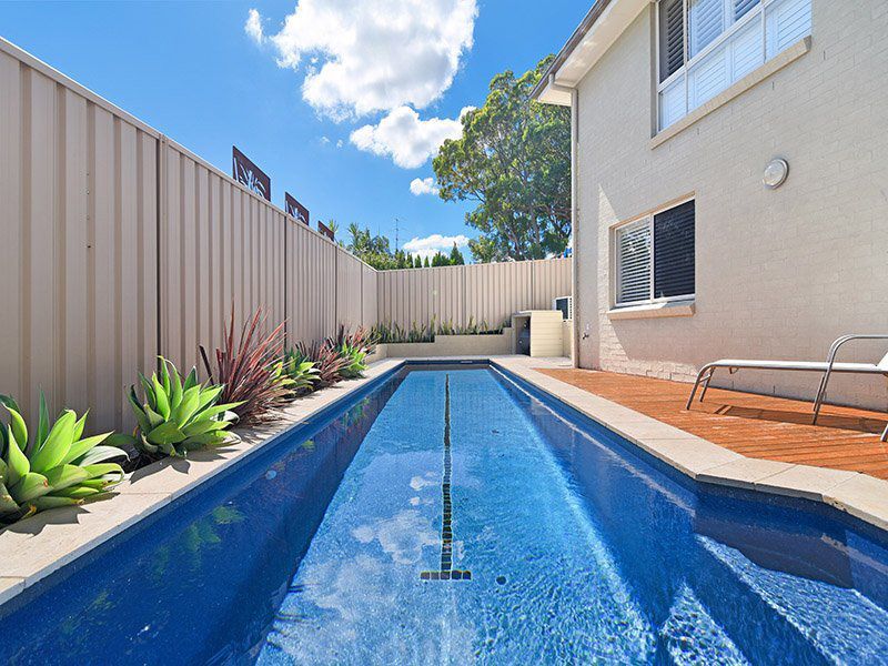 A Large Swimming Pool In The Backyard Of A House — Pool Installation in Newcastle, NSW