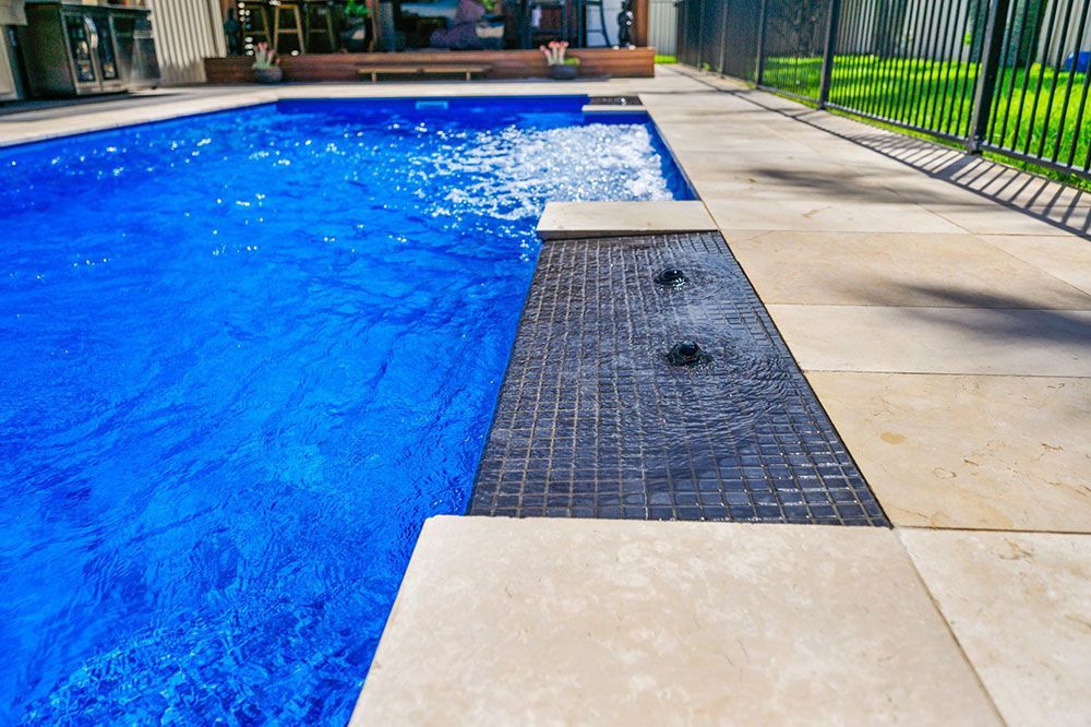 A Large Swimming Pool With Blue Water And A Fence Around It — Plunge Pools in Newcastle, NSW