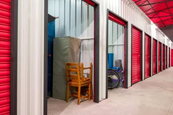 Storage units with red doors, a chair, and a mattress inside.