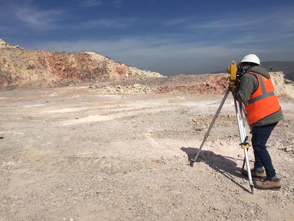 Un hombre con un chaleco naranja usa un trípode en el desierto.