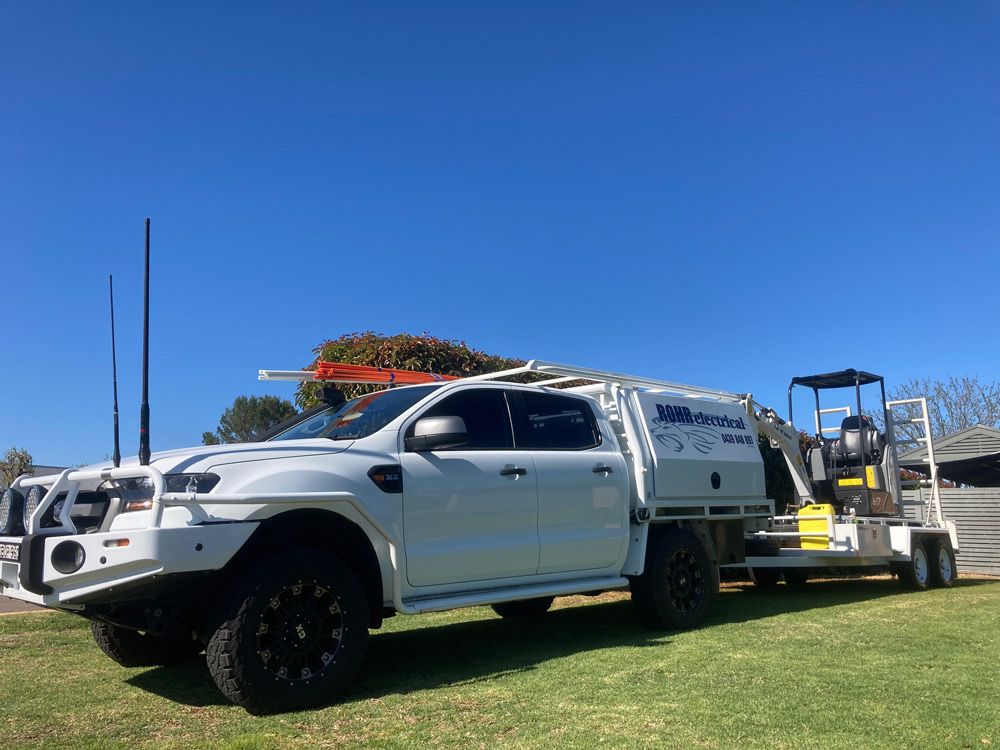 White Truck With Mounted Equipment and Trailer on Grass — Rohr Electrical in Dubbo, NSW