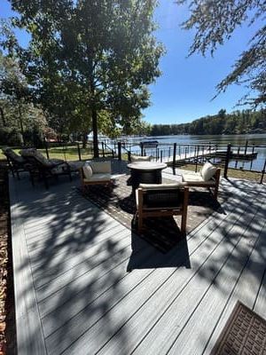 Sunny lakeside deck with outdoor chairs, tables, and trees overlooking the water
