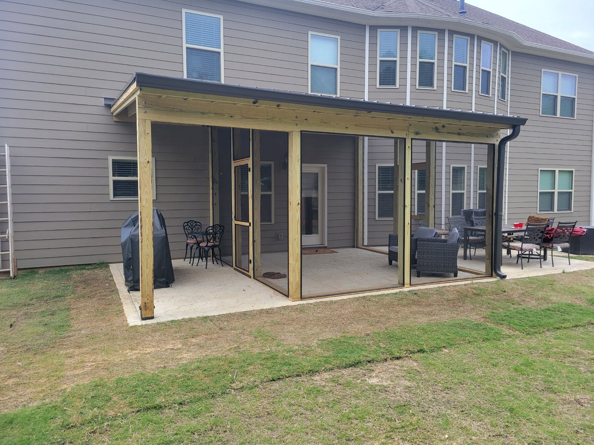 Covered patio with wooden posts attached to a beige townhouse