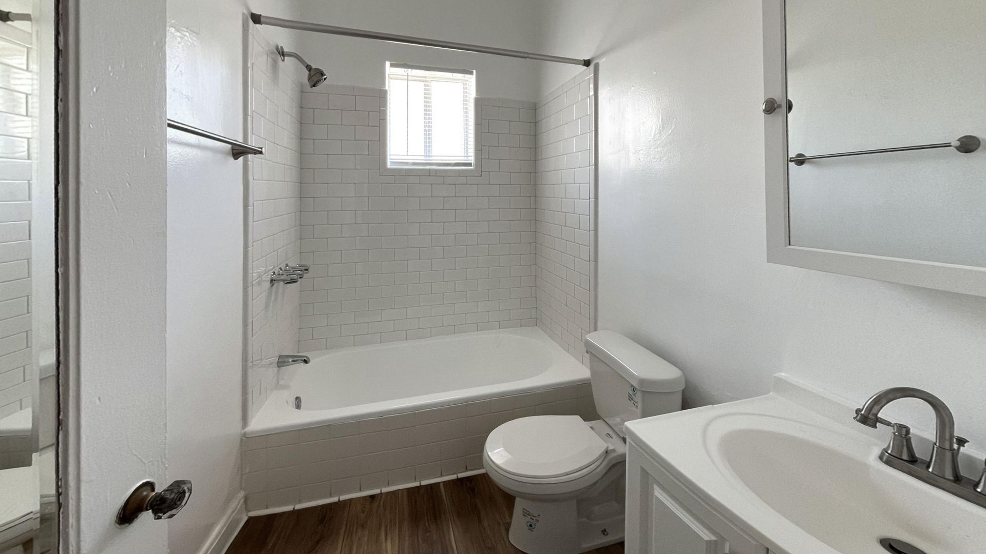 White bathroom with a bathtub, toilet, sink, and window.