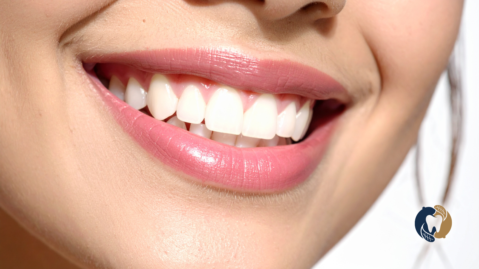 Close-up of a smiling mouth with white teeth and pink lipstick