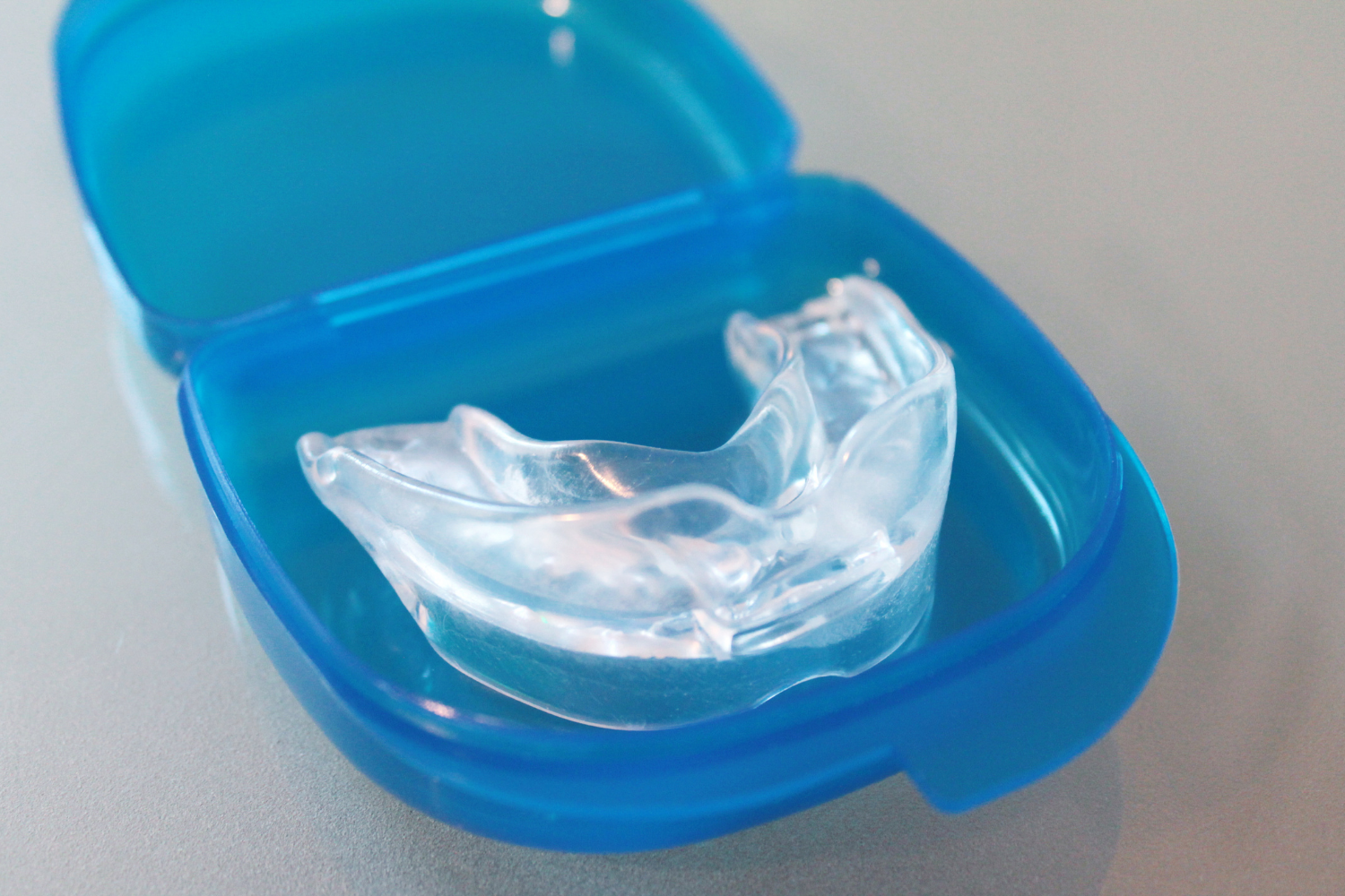 A clear plastic dental guard resting inside a small, open blue protective case.