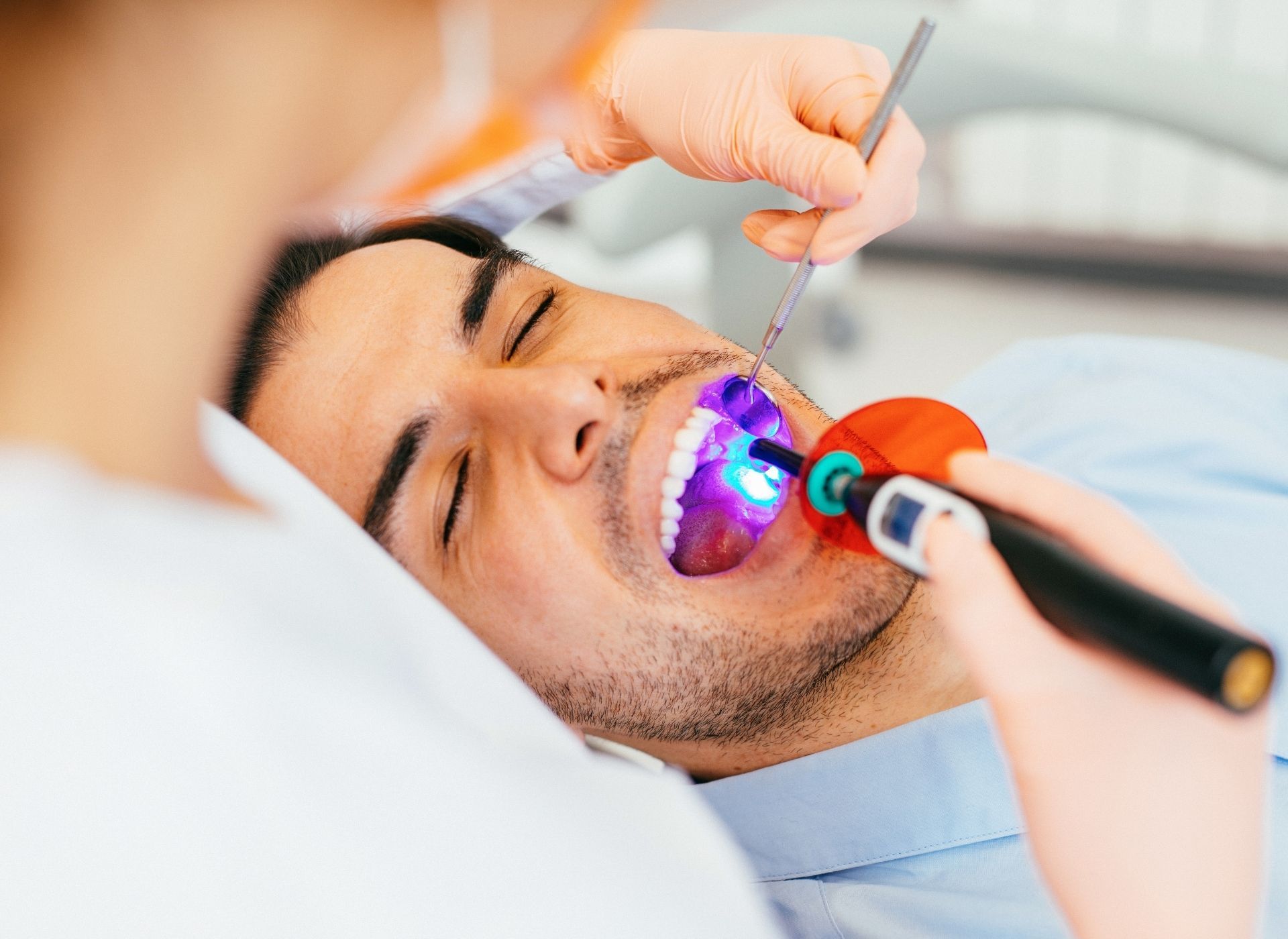 Close-up of a person using their hands to place a clear plastic dental aligner over their top teeth.
