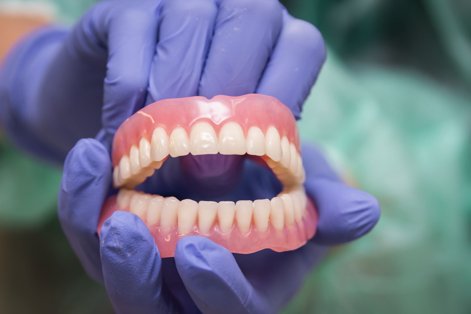 a person wearing purple gloves is holding a denture in their hands .
