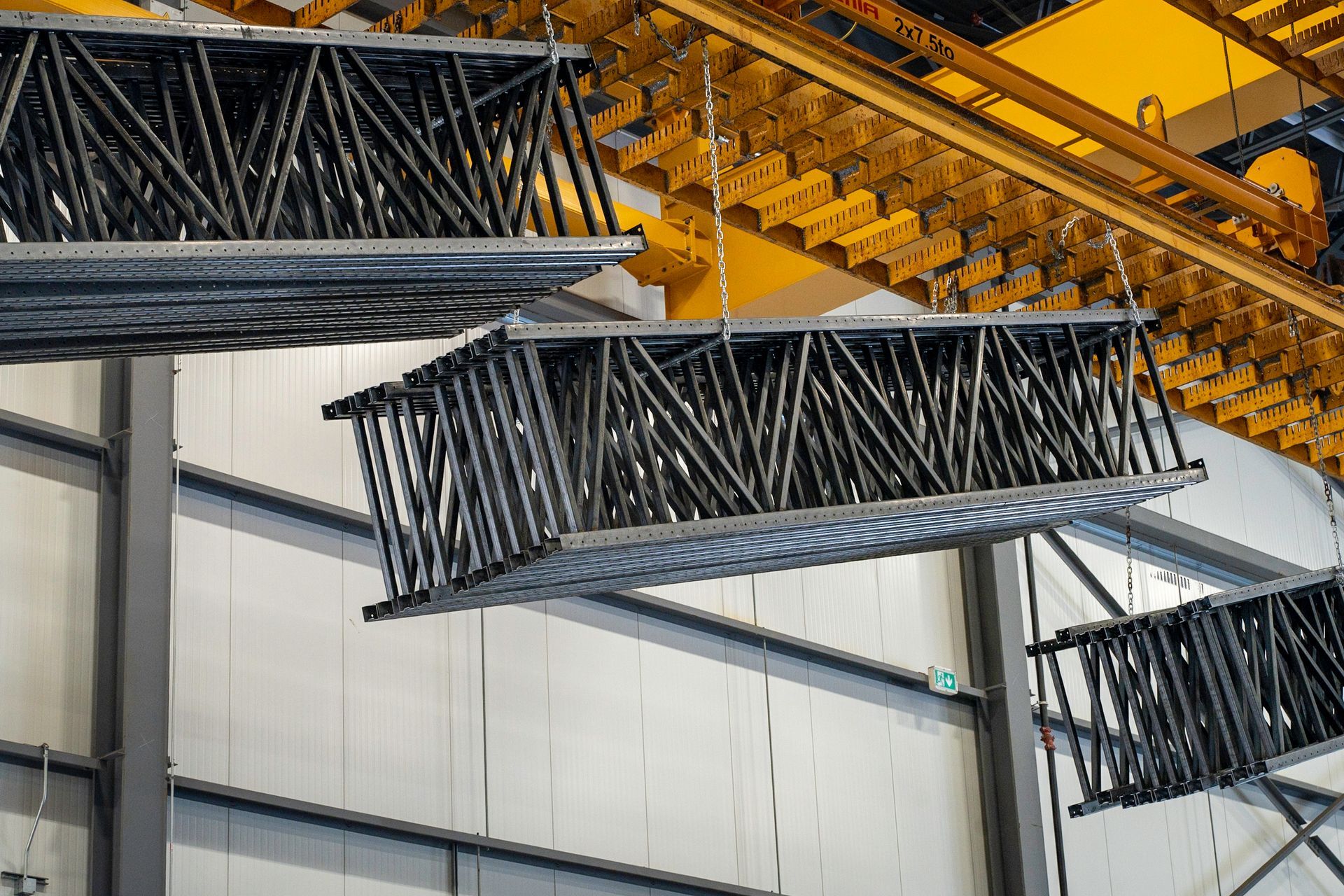 Metal trusses hanging from an industrial ceiling. Black and gray, possibly for construction.