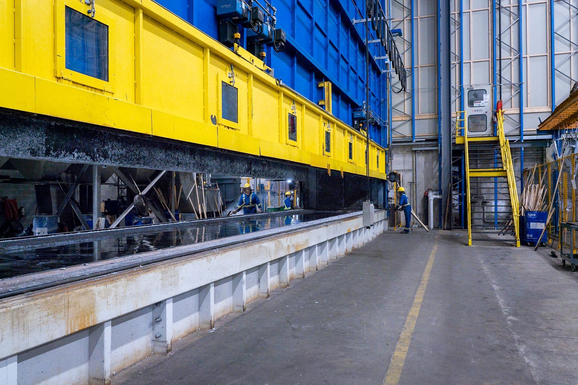 Yellow and blue industrial machinery with workers in a factory setting.