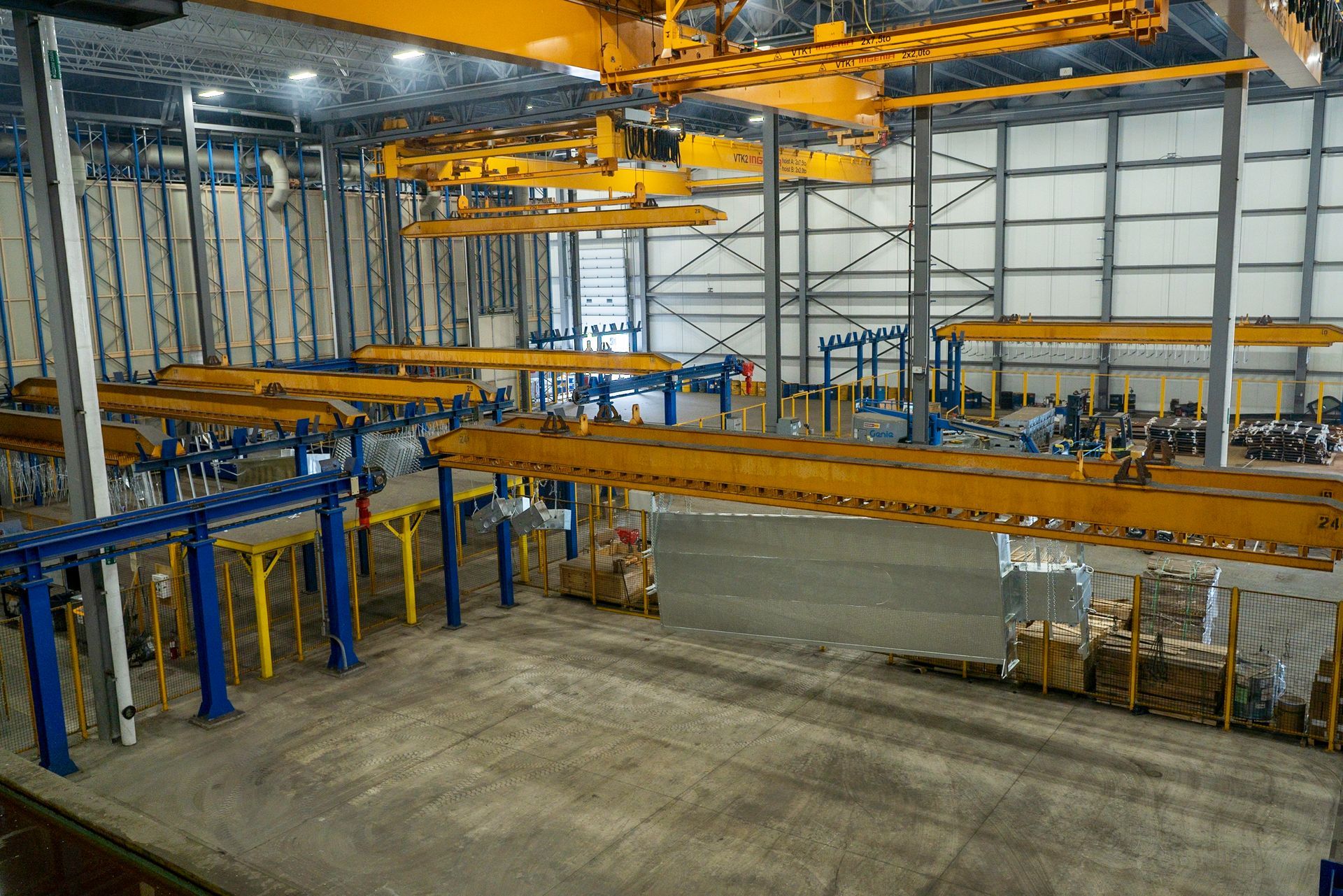Overhead cranes in a large industrial facility. Yellow and blue machinery.