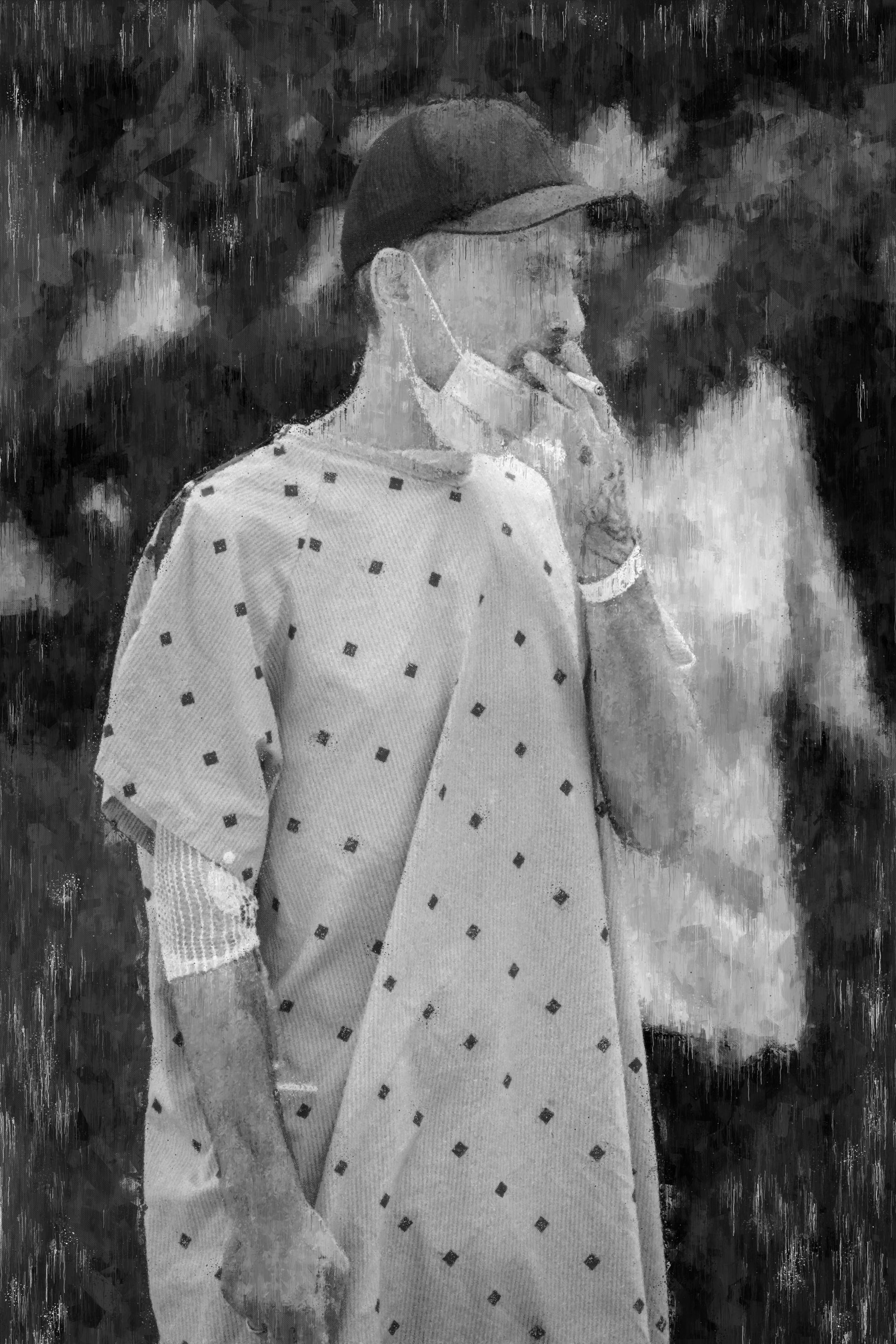 Person in medical gown and baseball cap, outdoors, holding something to their face.