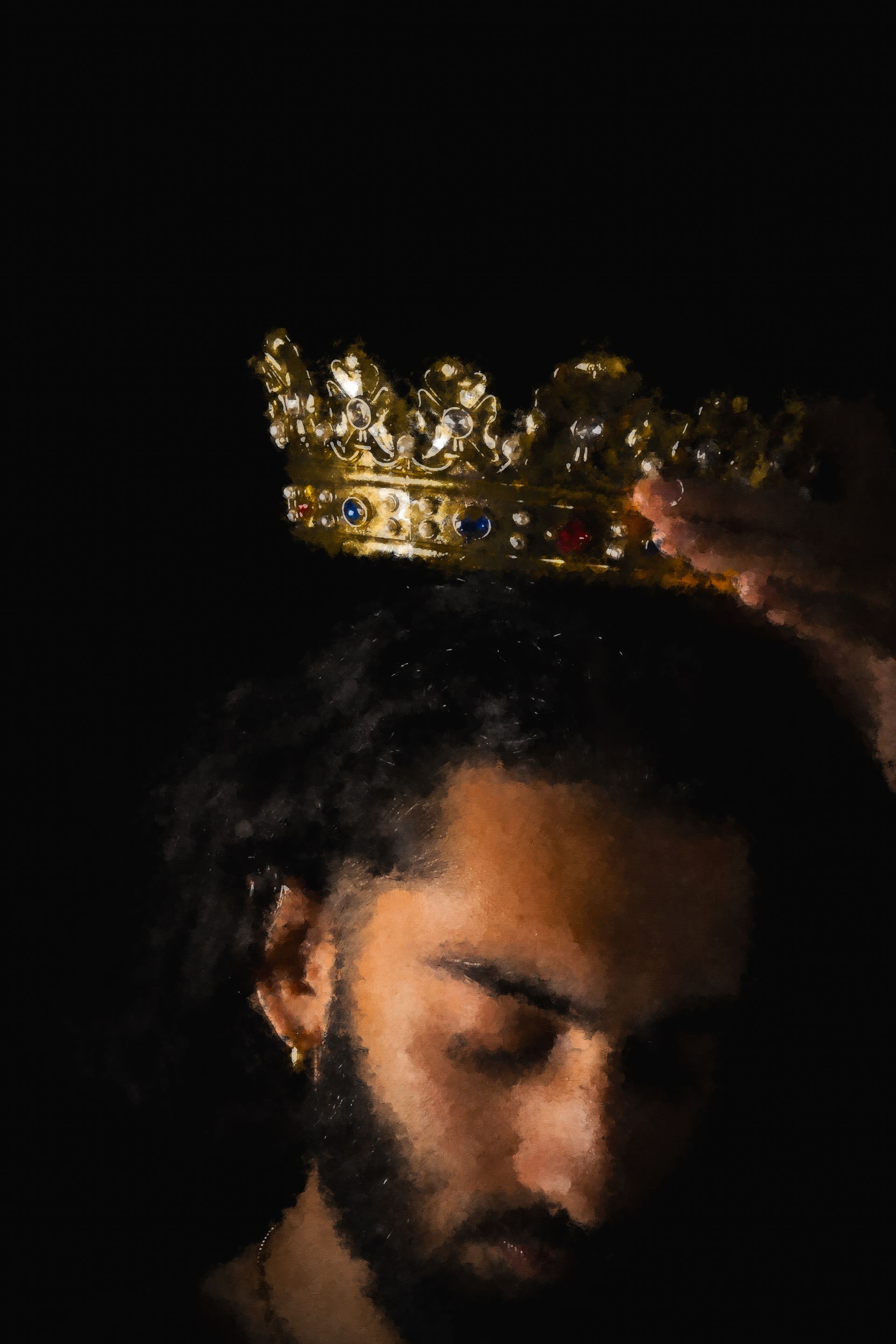 Hand placing a golden crown on a person's head, against a dark background.