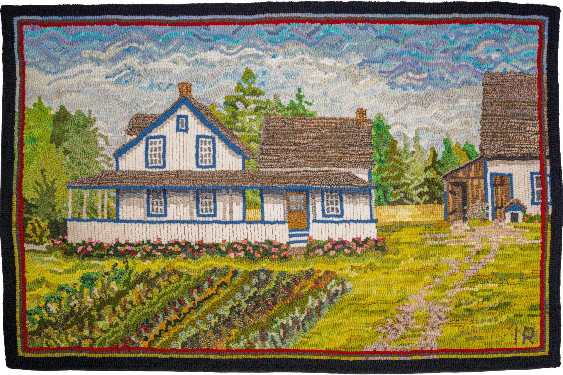 A rug depicting a white house with blue trim, brown roof, and a barn on a green lawn with a dirt path.