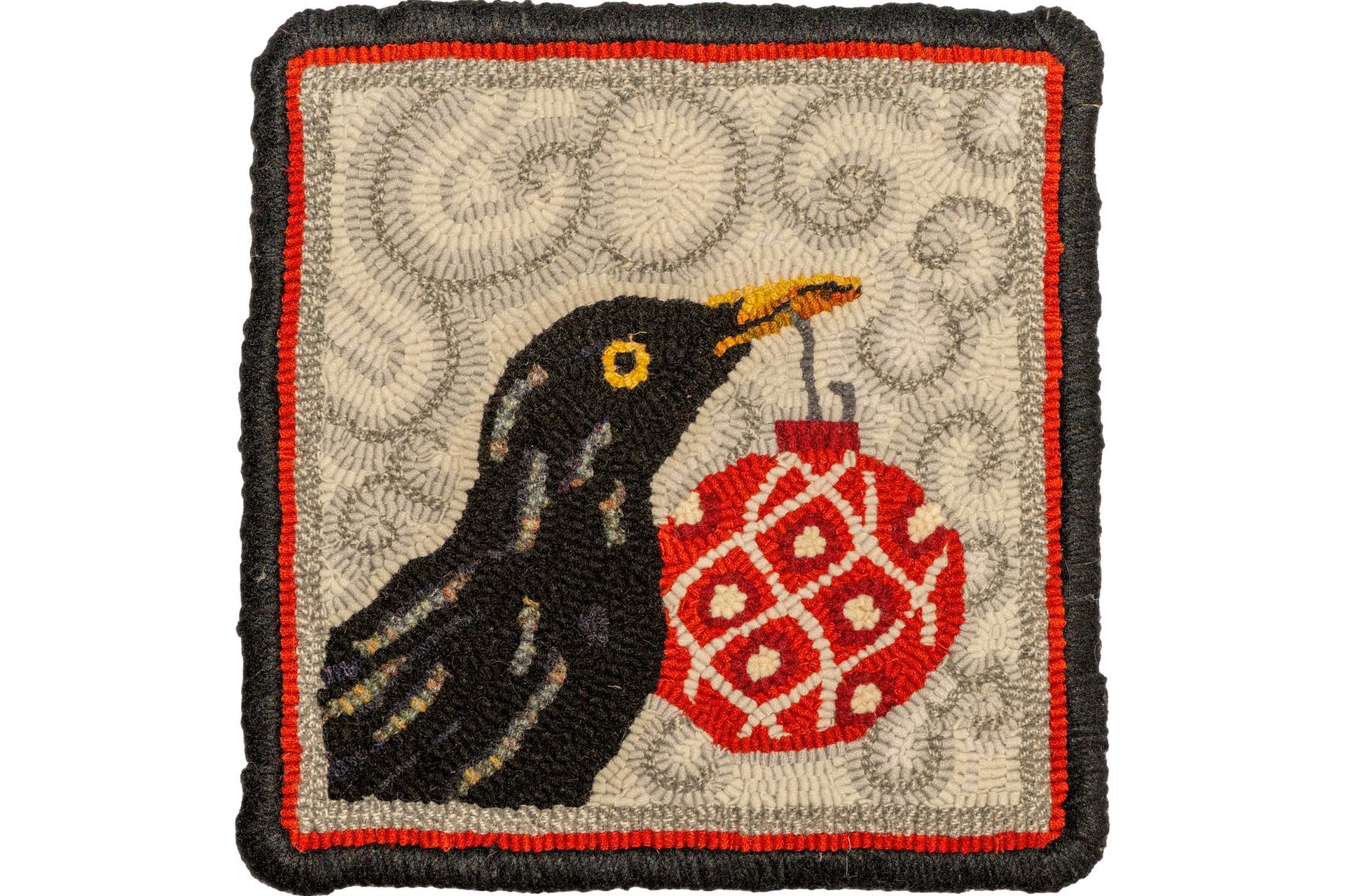 Blackbird holding a red ornament, against a swirl background, framed in black.