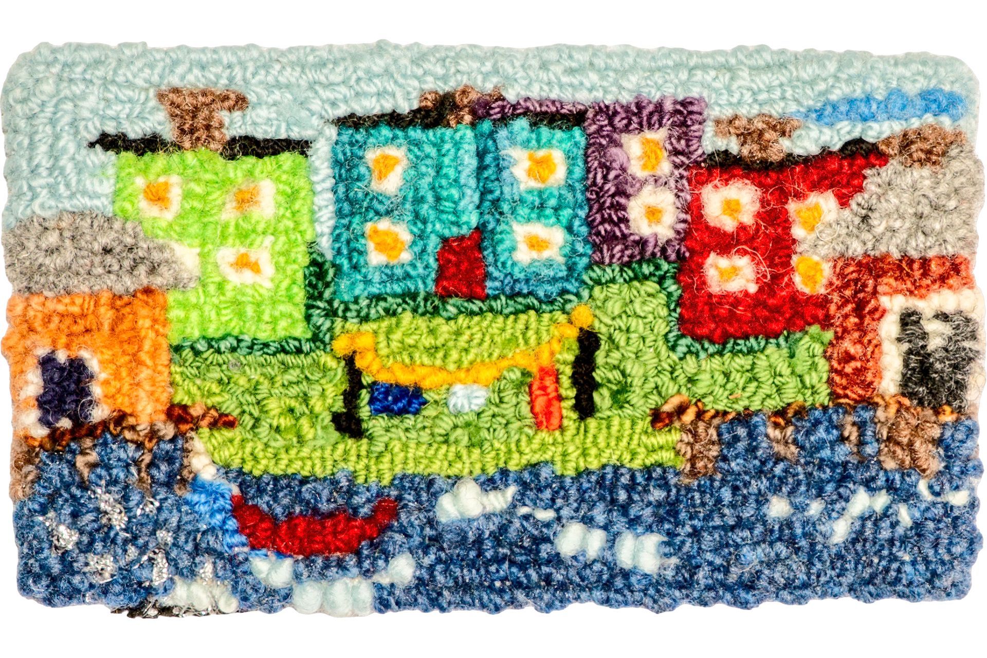 Colorful rug depicting a coastal town with buildings in green, turquoise, and red, plus a boat.