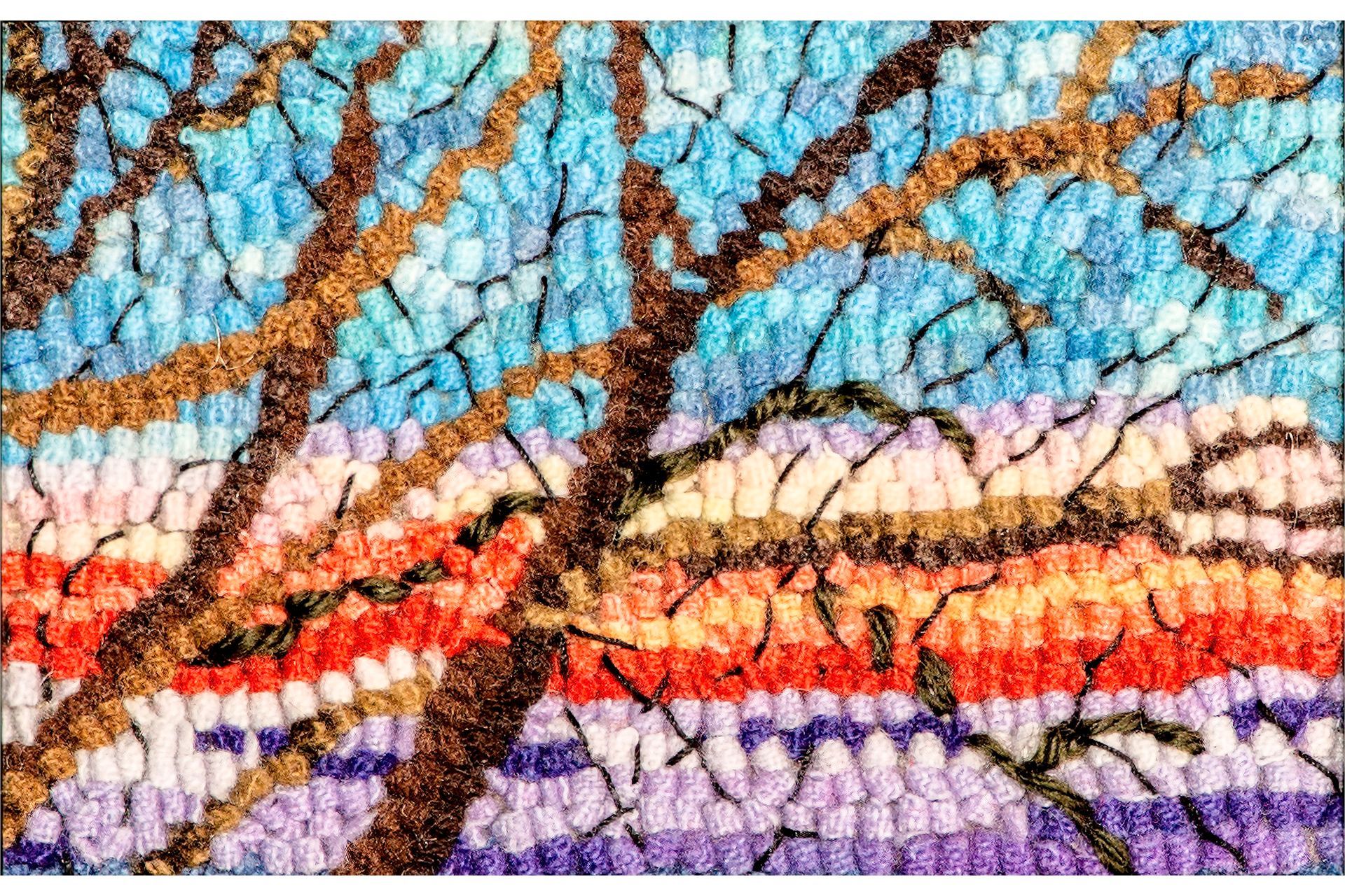 Tree branches against a woven backdrop of colorful sunset sky.