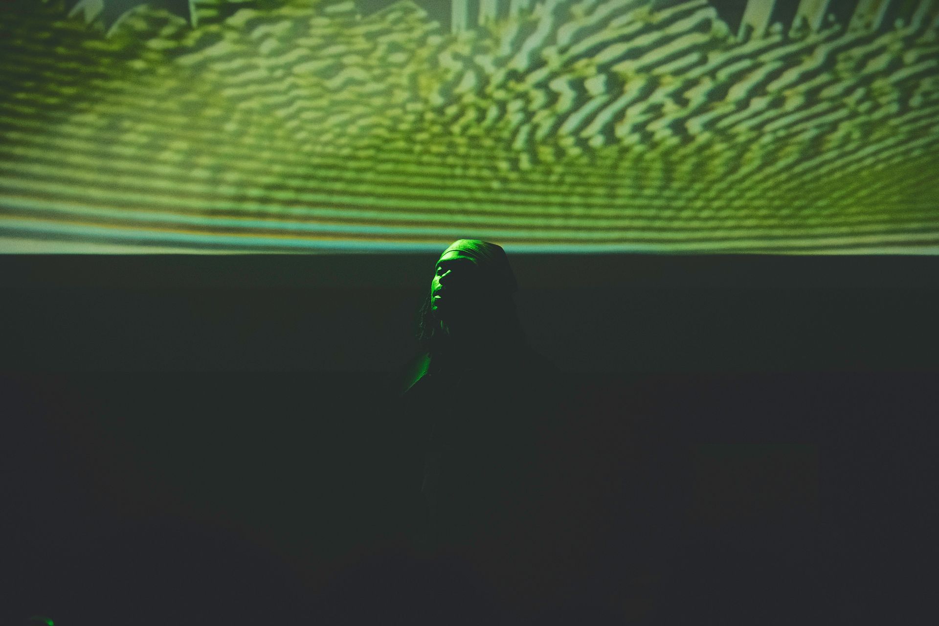 A green, glowing object against a dark background, with a blurry green and white pattern above.