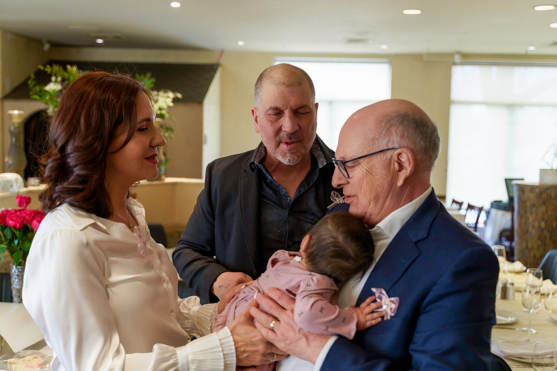 Woman, two men, and baby at table; man holding baby, others look on.