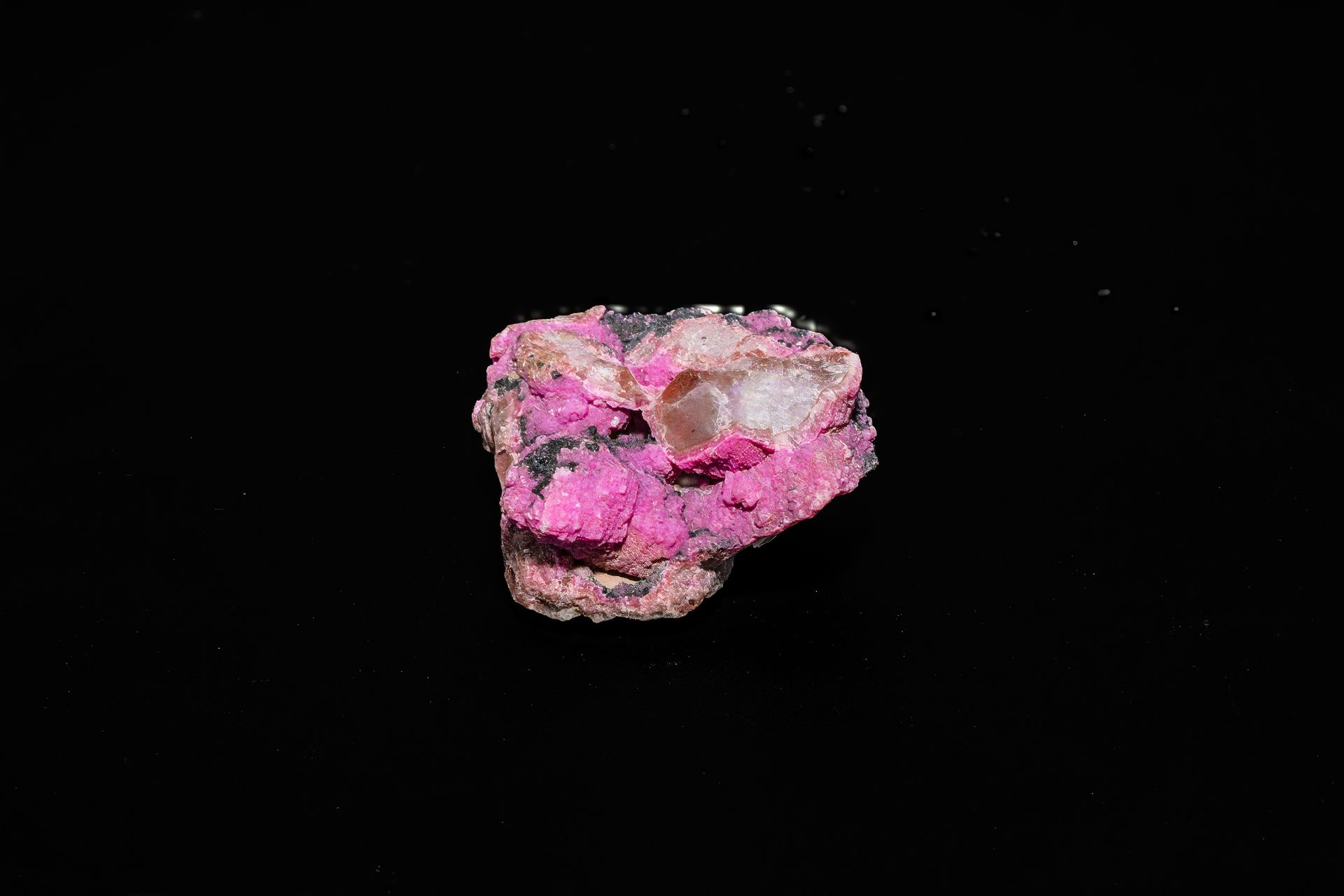 Pink and white mineral specimen against a black background.