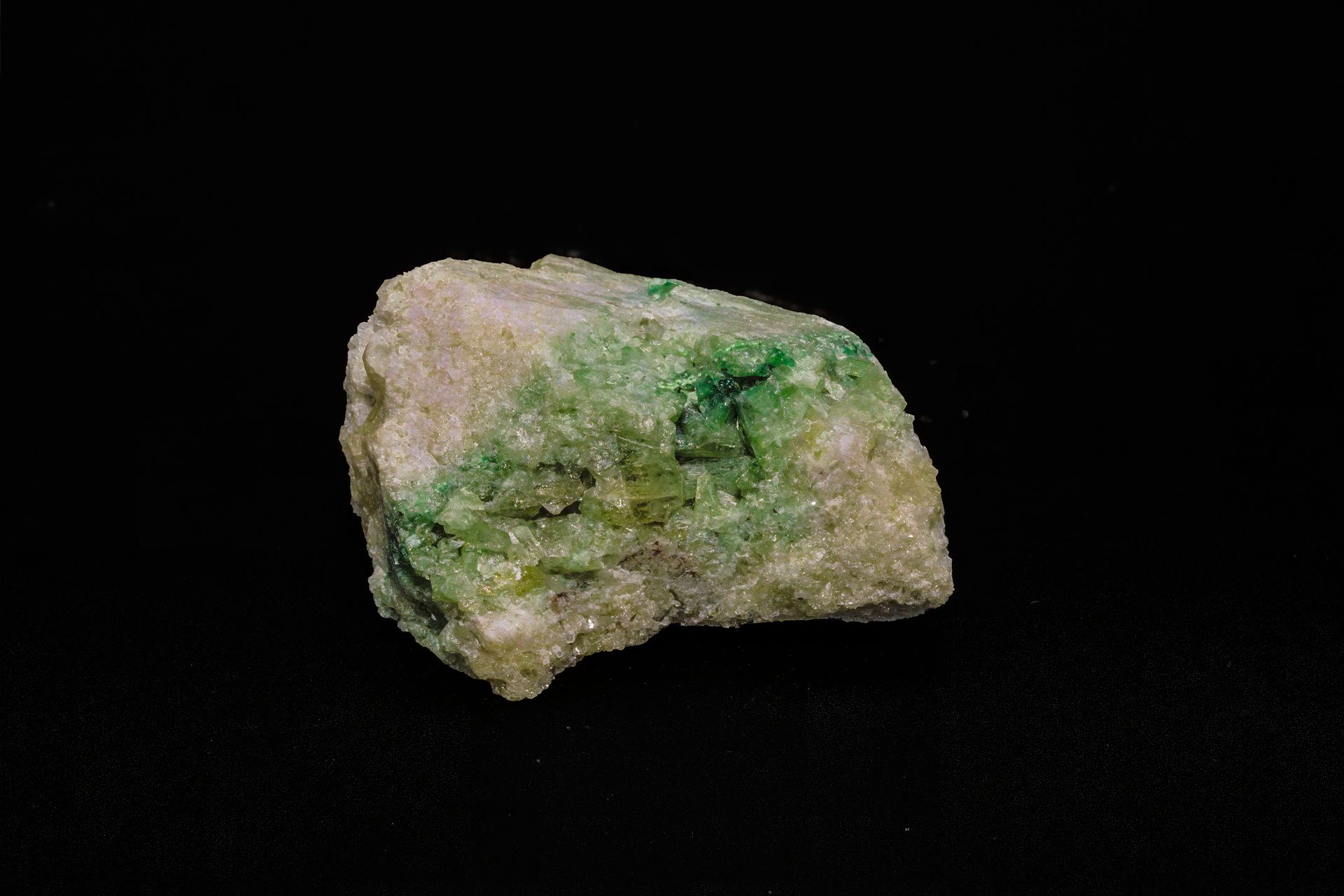 Green and white mineral specimen on a black background.