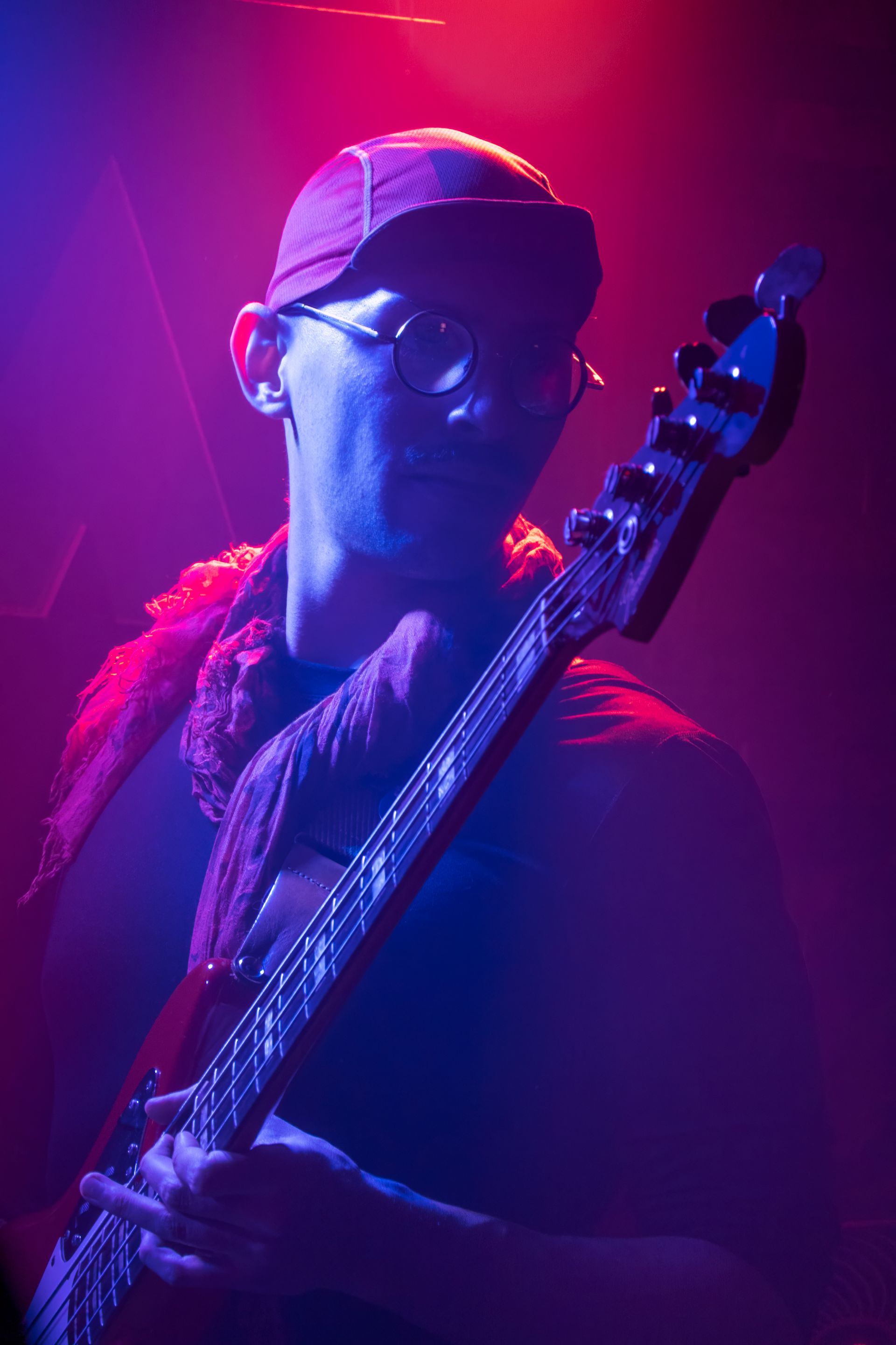 Drummer playing a drum kit on a stage with bright blue lighting.