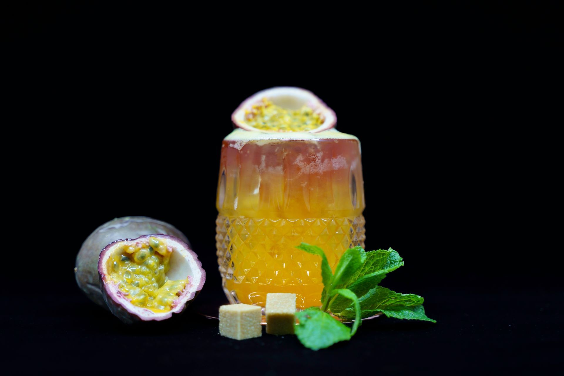 Passion fruit cocktail with garnish on black background.