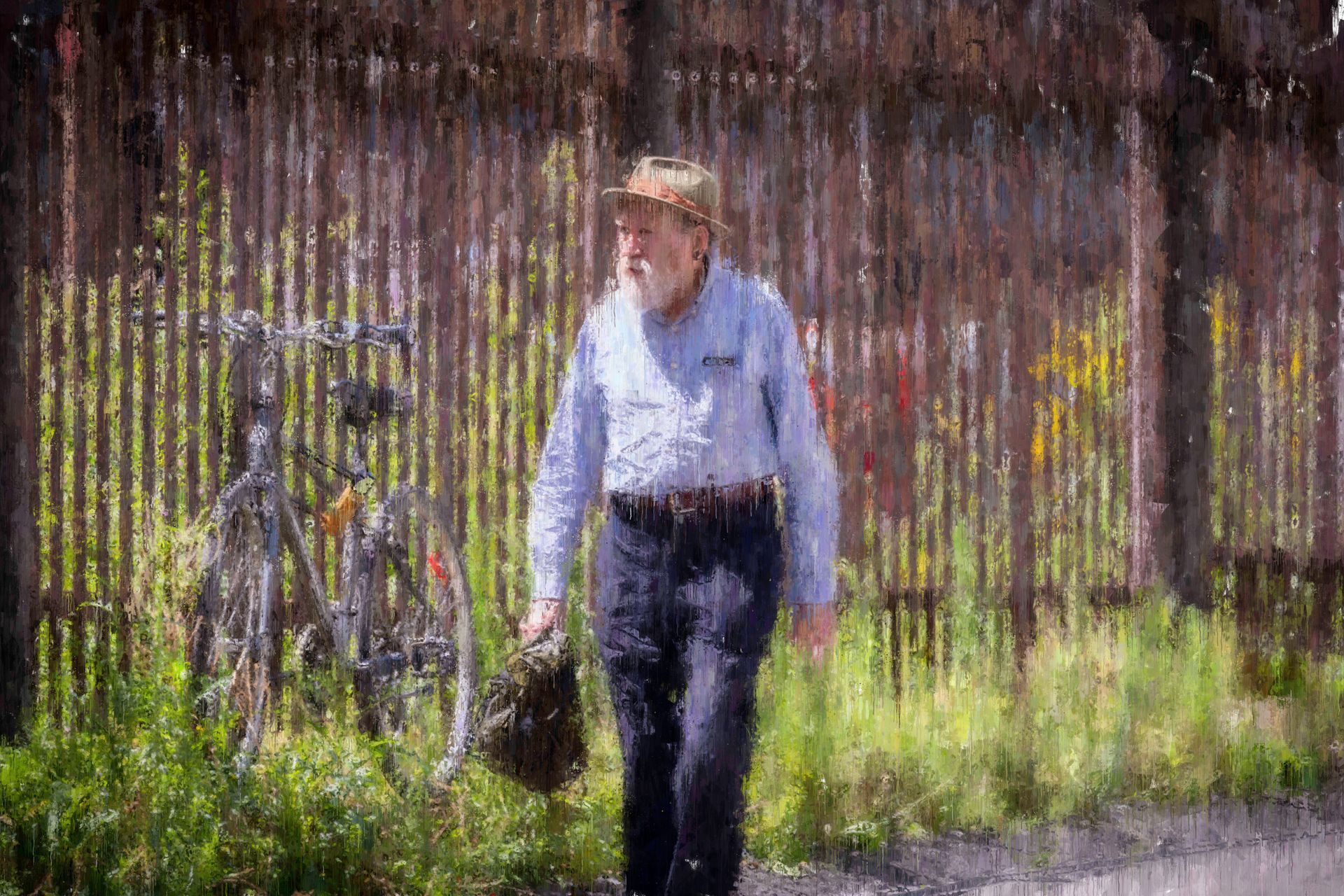 Man walking with bag past bicycle near a fence.
