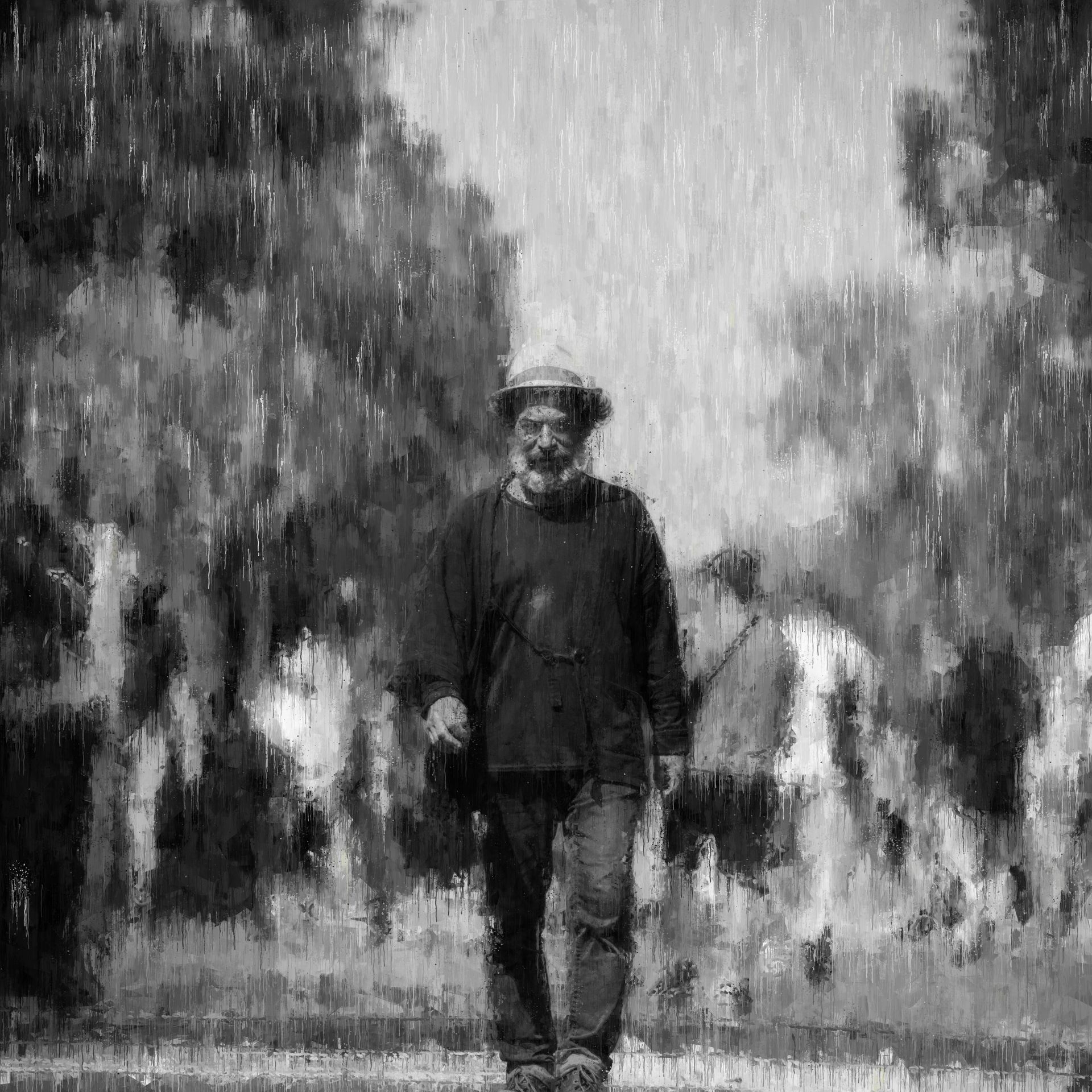 Man in hat walking in the rain, surrounded by trees. Black and white.