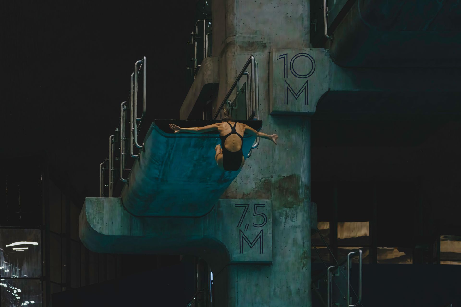 A person diving into water from a concrete structure at night.
