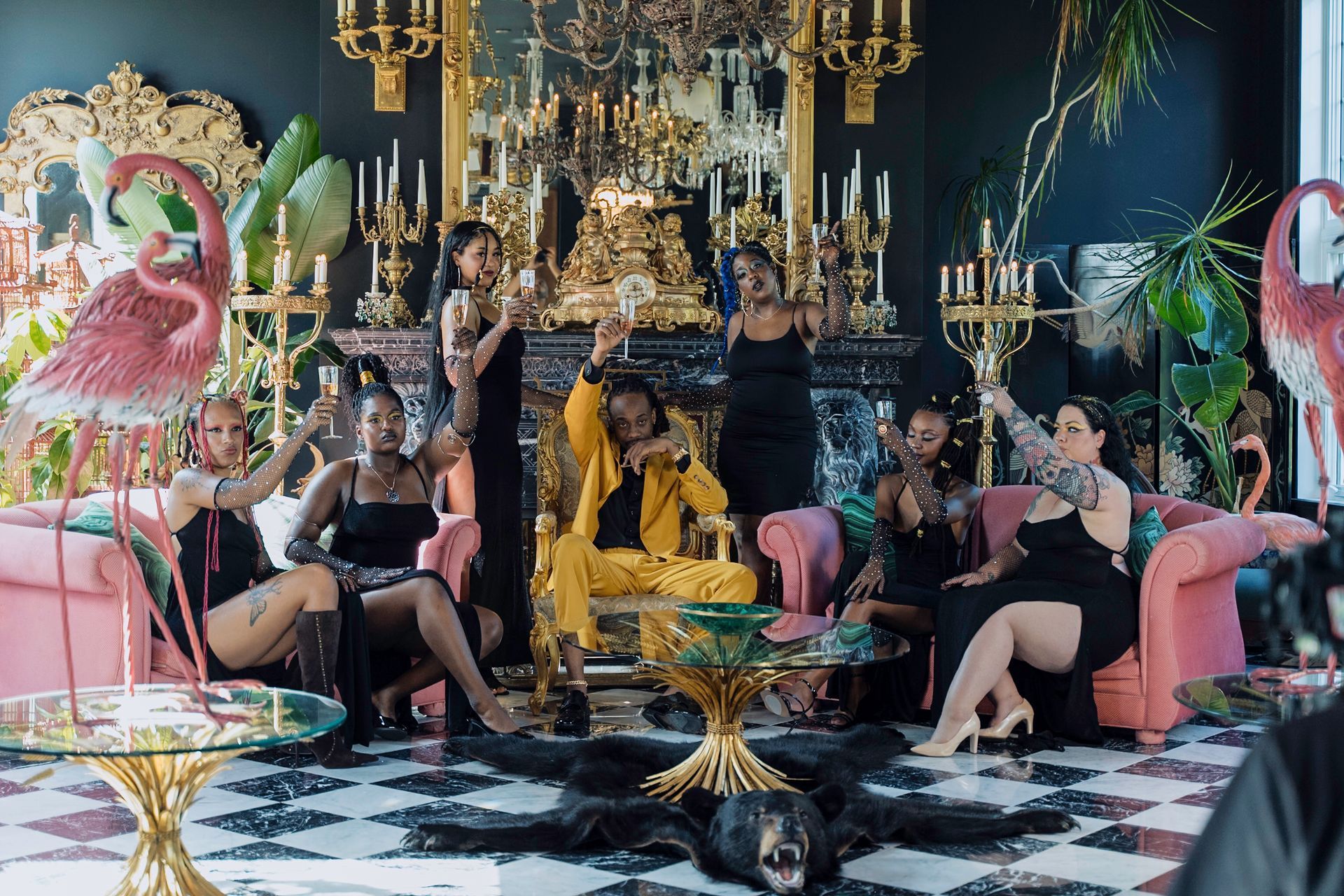 Group of people toasting in a luxurious room.  Ornate gold accents and pink seating.