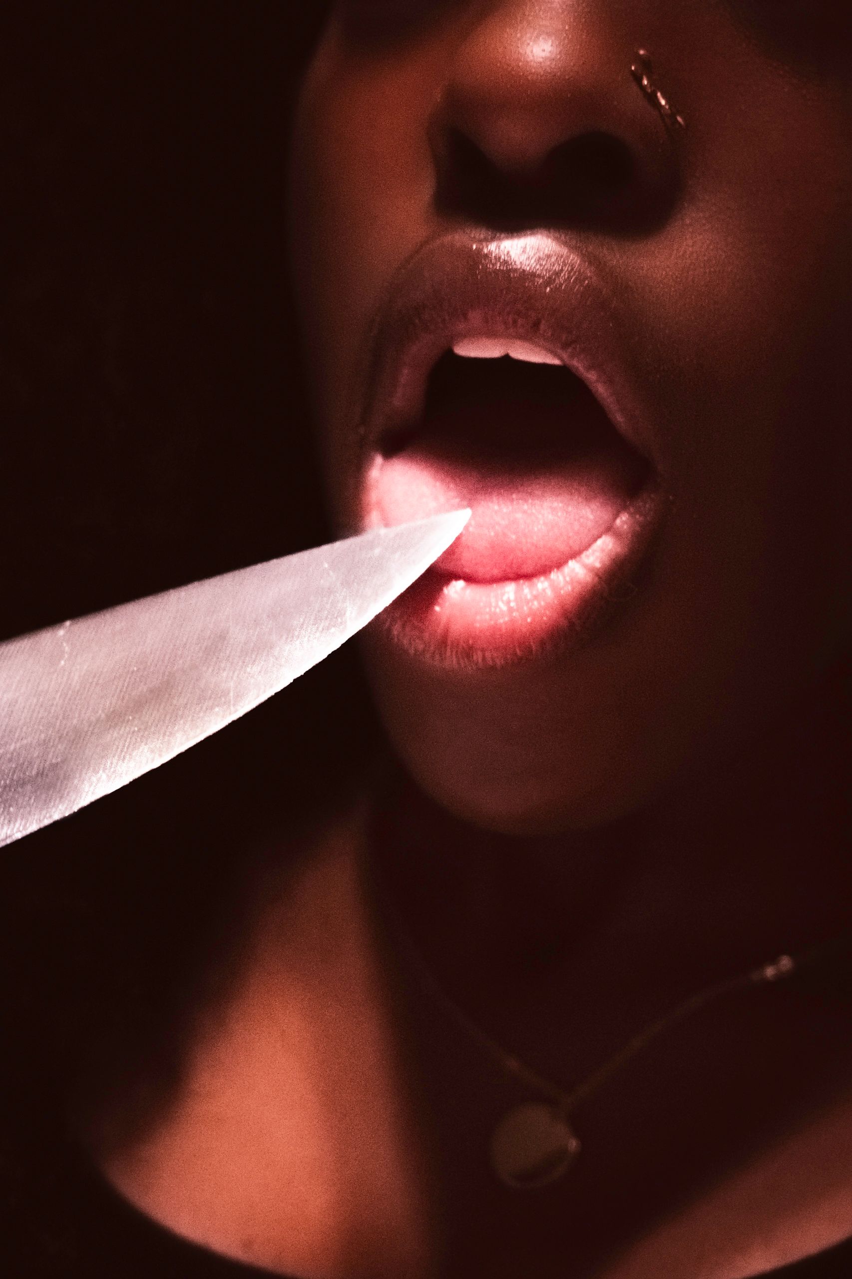 Mouth open, tongue visible. Knife blade pointed towards the tongue.
