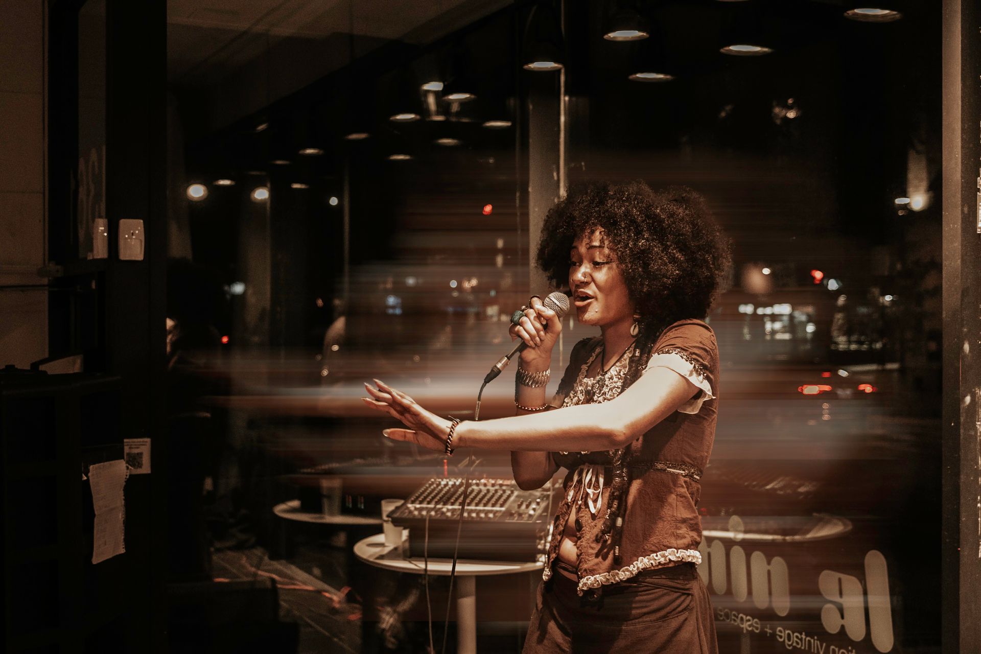 Woman singing into a microphone on a stage in a dimly lit venue.