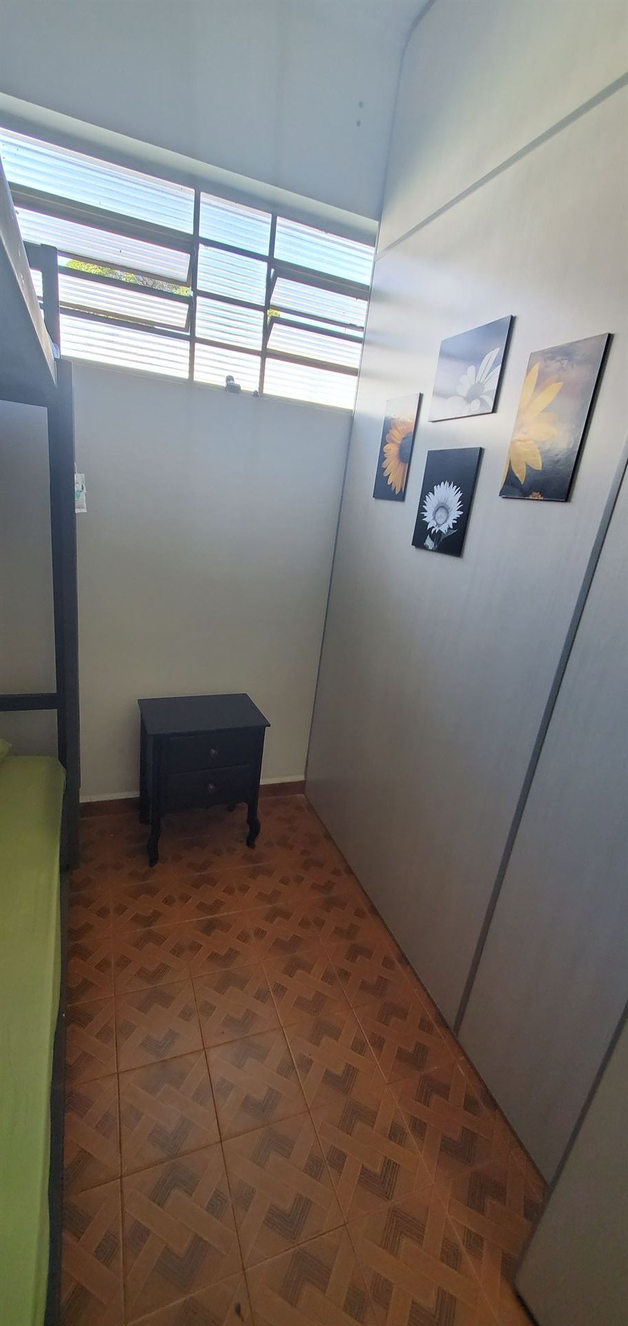 Um quarto com beliches, uma mesa de cabeceira e uma janela.