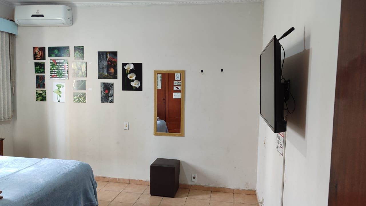 Um quarto com cama, televisão, espelho e ar condicionado.