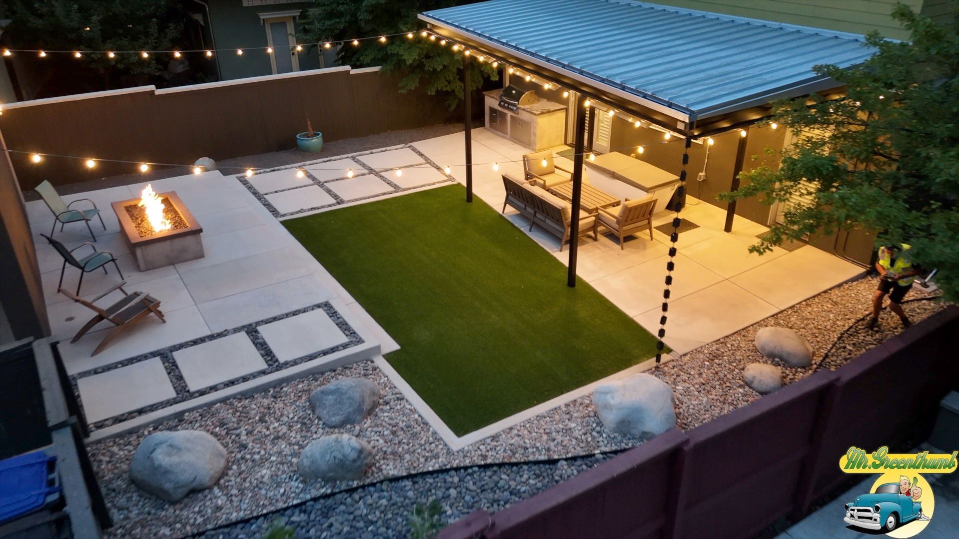 Backyard patio with a fire pit, artificial turf, a pergola with dining area, and string lights.
