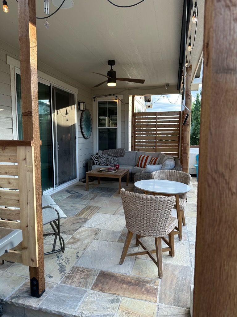A patio with a couch , chairs , tables and a ceiling fan.